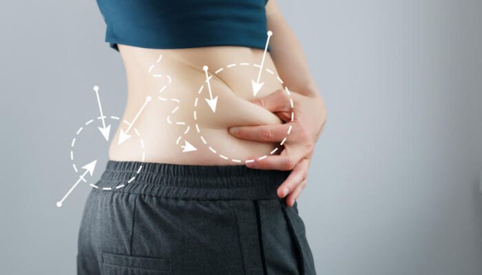 Skinny fat woman figure in fitness clothes touches stomach. Abdominal fat and dieting concept. Massaging marks.